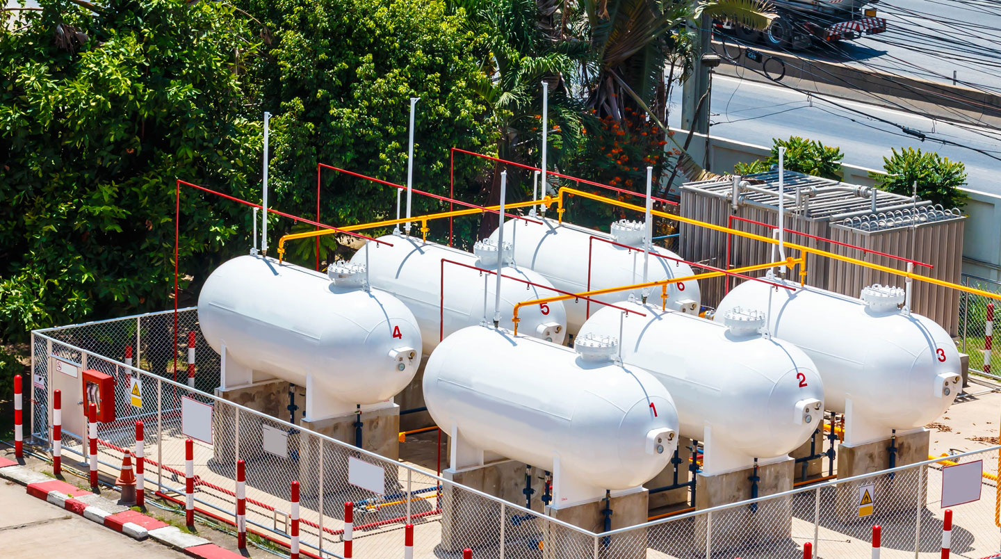 Citerne de gaz propane installée sur un site industriel professionnel avec des bâtiments tertiaires en arrière-plan