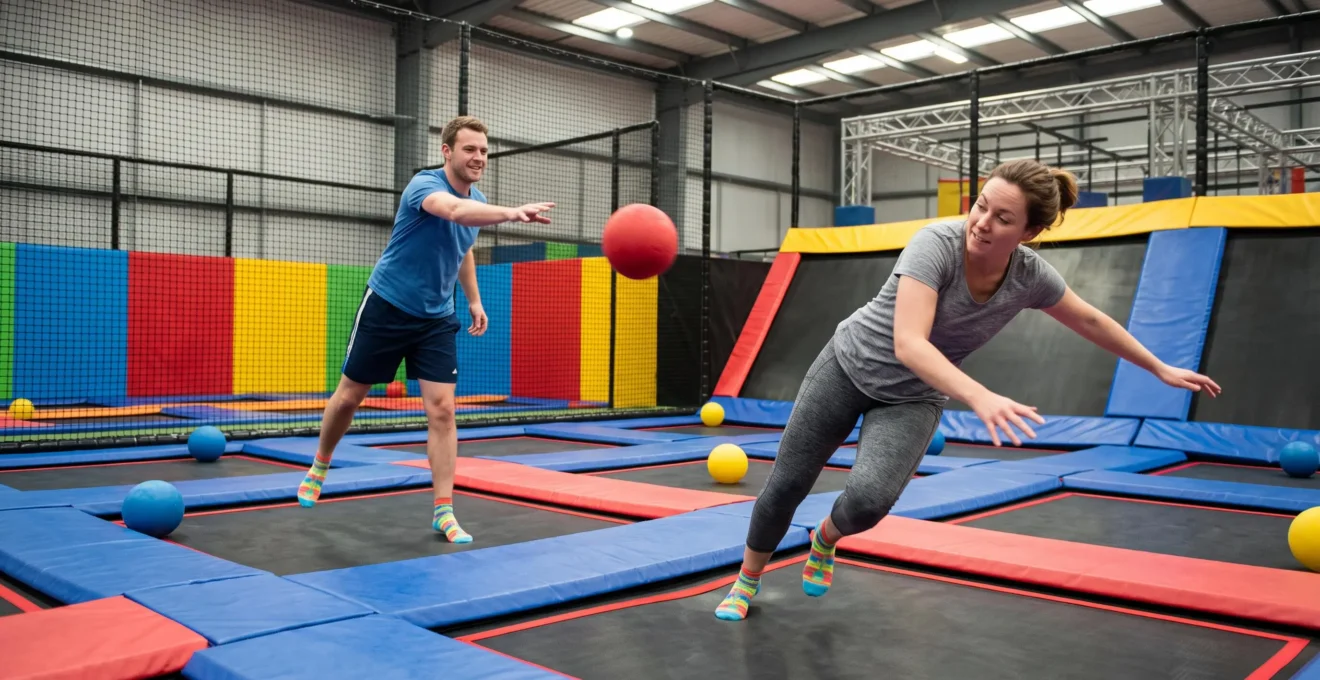 Deux collègues jouent au dodgeball sur une zone de trampolines dans un parc indoor.